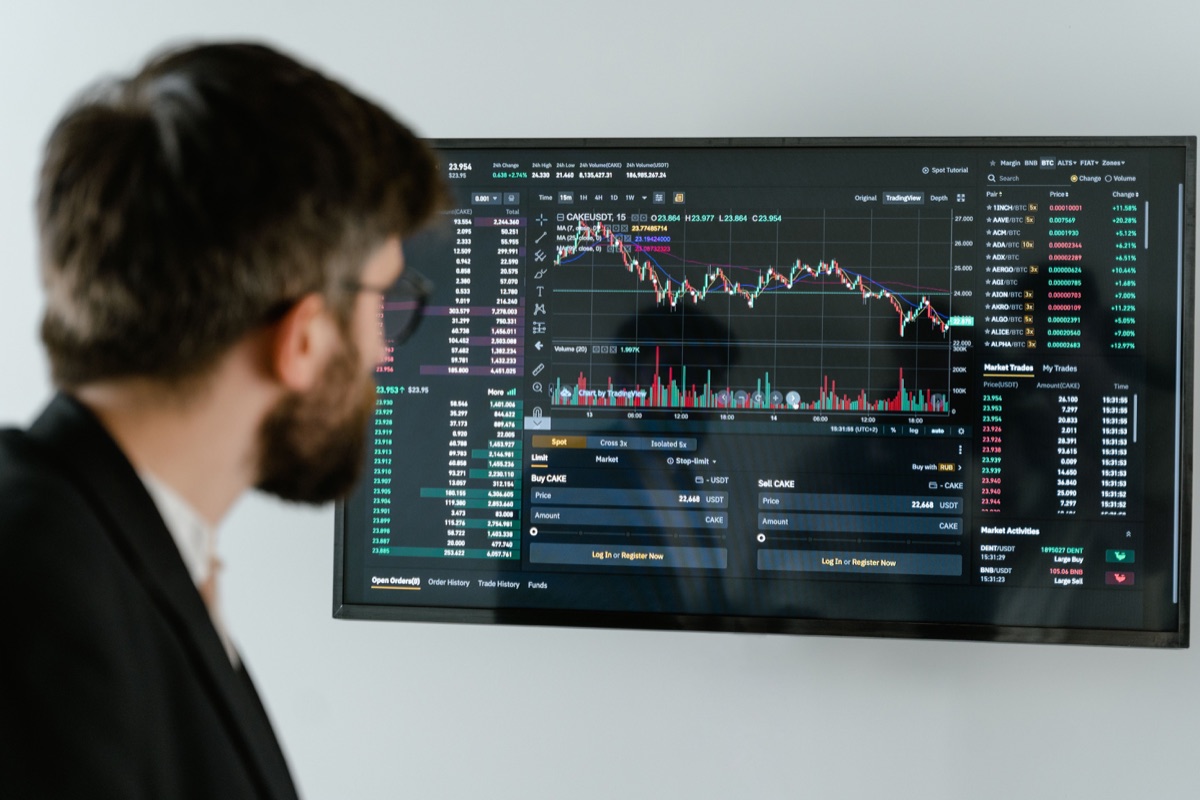 Finansal grafiklerin açık olduğu büyük ekranı inceleyen kişi