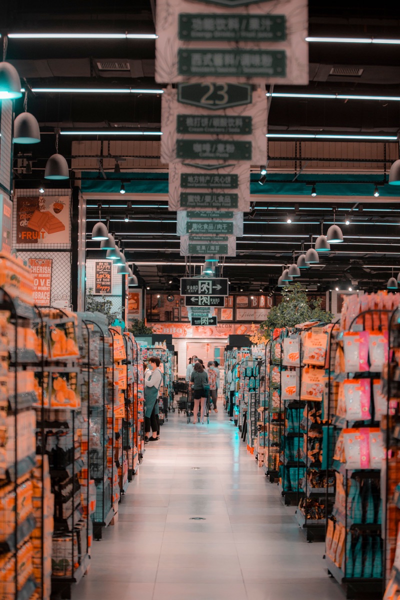 Market koridorunda ürün rafları ve yönlendirme tabelaları